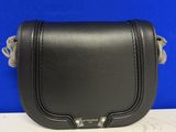 un sac à bandoulière en cuir noir posé sur une table blanche