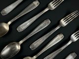 beaucoup de cuillères et de fourchettes en argent posées sur une table noire