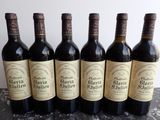 six bottles of wine are lined up in a row on a table