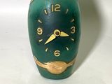 une bouteille verte ornée d'une horloge, à côté d'un petit oiseau