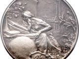 an image of a silver medal with a woman sitting on a rock