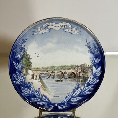 une assiette bleue et blanche sur laquelle est représenté un pont