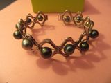 bracelet en argent orné de perles noires sur un fond rose