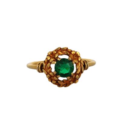 a close up of a gold ring with a green stone