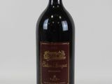 une vieille bouteille de vin rouge posée sur une table blanche