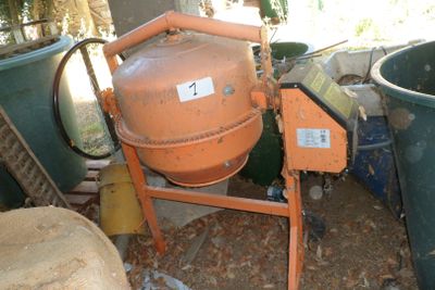 une bétonnière orange posée au milieu d'un tas d'ordures