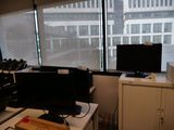 un bureau équipé de deux écrans et d'une imprimante, placé devant une fenêtre