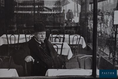 photographie en noir et blanc d'un homme assis à une table dans un restaurant