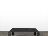 une photo d'une table basse noire posée sur un sol en béton