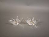 une paire de bougeoirs en verre transparent posés sur une surface blanche