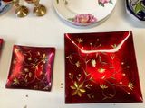 a red plate with gold flowers on it next to other plates