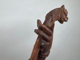 wooden sculpture of a hand holding a snake on a white background