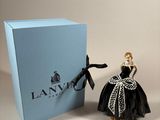 a small figurine of a woman in a black dress next to a blue box