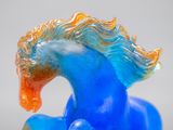 a blue and orange glass horse that is on a table