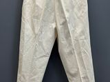 a white pants hanging on a hanger against a gray wall