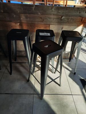 trois tabourets en métal posés devant un mur en bois