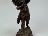 figurine en bronze représentant un garçon tenant une fleur dans ses mains