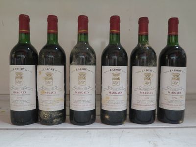 six bouteilles de vin sont alignées sur une table