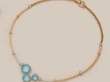a gold necklace with blue stones and diamonds on a beige background