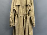 un trench-coat beige accroché au mur