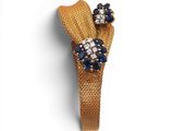 un gros plan d'une broche en forme de fleur dorée et bleue sur fond blanc