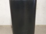 a black trash can sitting on the floor next to a white wall