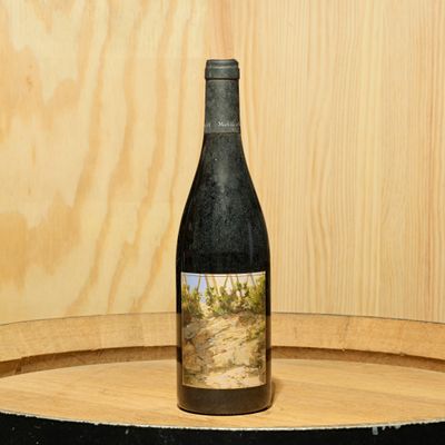 a bottle of wine sitting on top of a barrel