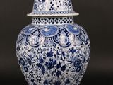 blue and white vase with a bird on top of it on a table