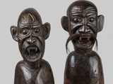 pair of carved wooden figurines of two men with different facial expressions