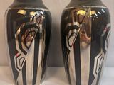 une paire de vases noirs et argentés posés sur une surface blanche