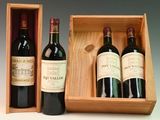 three bottles of red wine in a wooden box on a table