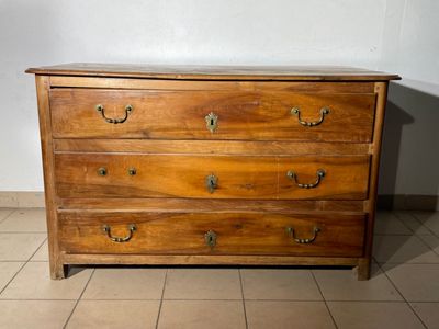 a wooden chest of drawers on a tiled floor