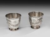 deux tasses en argent posées l'une à côté de l'autre sur une table