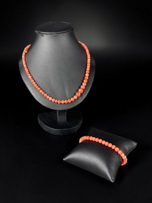 an orange beaded necklace and a black pillow on a black background