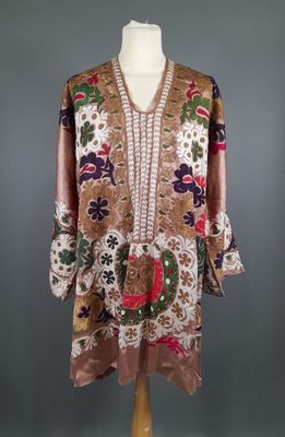 une robe posée sur un mannequin, ornée de fleurs et de feuilles