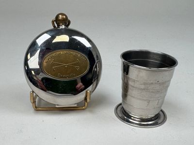 une tasse en argent posée à côté d'une flasque en argent sur une table