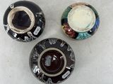 three black and white vases sitting on top of a white table