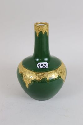 a green vase with gold decoration on it on a white surface