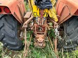 un tracteur qui est garé dans l'herbe près d'un bâtiment
