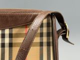 the brown and tan plaid purse is sitting on a gray surface
