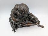 bronze statue of a boy sitting on a chair with his hands on his knees