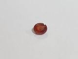 an oval shaped red garnetite stone on a white surface