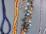 several necklaces of various colors and shapes are displayed on a table