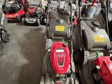 Plusieurs tondeuses à gazon sont alignées dans un garage
