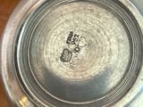 a silver plate on a table with a cup and saucer
