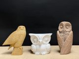 trois figurines de chouettes posées les unes à côté des autres sur une table