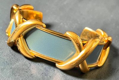 HERMÈS Bracelet jonc rigide en métal doré et cuir bleu