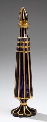 un vase bleu et doré posé sur un socle, sur une surface grise