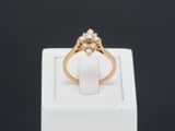 une bague en or jaune sertie de trois diamants, posée sur un écrin blanc