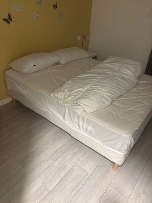 a bed that has a white comforter on it in a room